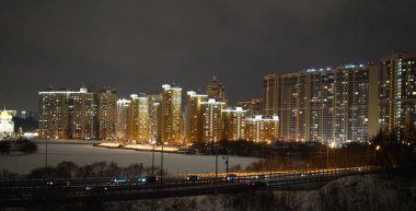 Moskova, Rusya - 16 Şubat 2021: Şehirde kış gecesi. Donmuş Moskova Nehri ve uzaktaki yüksek binaların ışıkları. Şehir manzarası