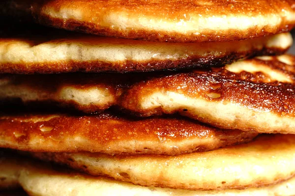 Altın krepler bir tabağın üzerinde, birbiri ardına. Yakın çekim..