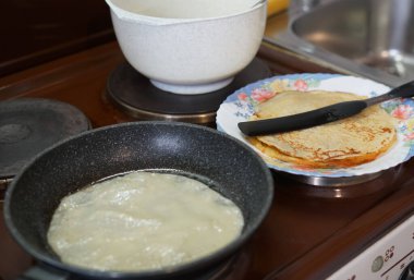 Evde, eski bir fırının üstünde gözleme pişiriyoruz. Kızartma tavasında, hamurda ve bir tabak hazır krepte.
