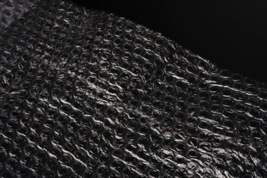 Siyah arkaplan dokusu üzerine baloncuk ambalajı. Sönük ışıklar.