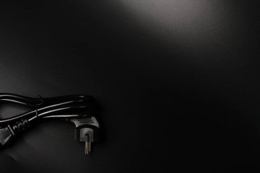 Bilgisayarın elektrik kablosu siyah arka planda ve metin için bir yerde siyahtır. Sönük ışıklar.