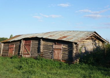 Eski ahşap ahır neredeyse yok oldu. Yaz ve yeşil çimenler her yerde
