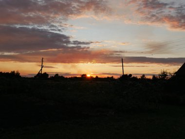 Şehrin dışındaki turuncu gün batımı tamamen karanlık. Sadece siyah ağaç tepeleri ve evler görülebilir. Güzel renkli bulutlar ve gökyüzü