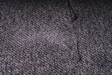 Yoğun koyu bir kumaşın dokusu ve çıkıntılı bir iplik.