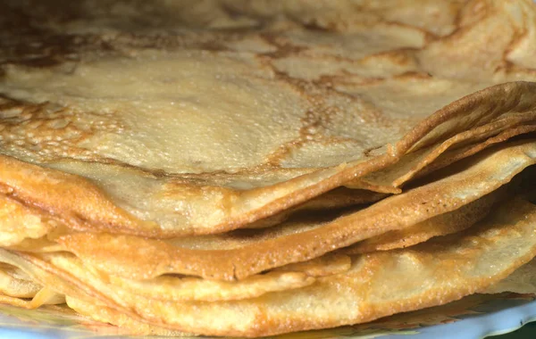 A stack of thin pancakes sits on a plate. Side view. Closeup — Stock Photo, Image