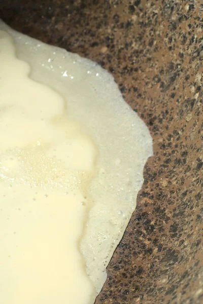 La crêpe liquide commence à frire dans une poêle. Photo verticale — Photo