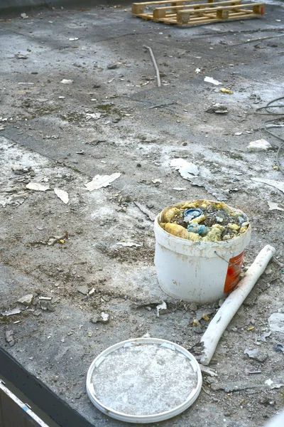 Construction debris is placed in a paint bucket. Vertical snapshot — Photo