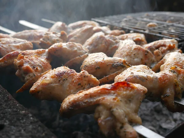 Le ali di pollo sono fritte su un fuoco aperto. C'è fumo tutt'intorno. Barbecue — Foto Stock