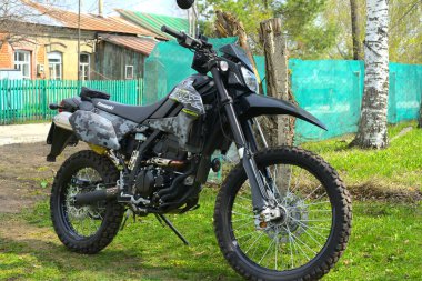 Moskova, Rusya - 14 Mayıs 2021: Şehrin dışındaki yeşil çimlerin arka planında yeni bir Kawasaki kros motosikleti. Bir bahar günü