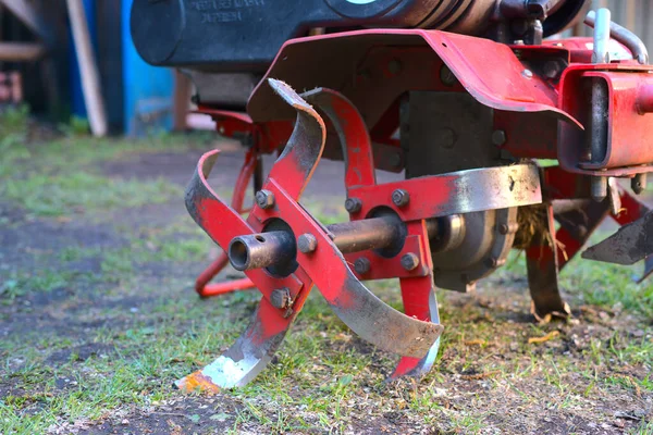 A mini tractor for plowing the land stands in the farmyard. The main lever that digs is visible. Closeup