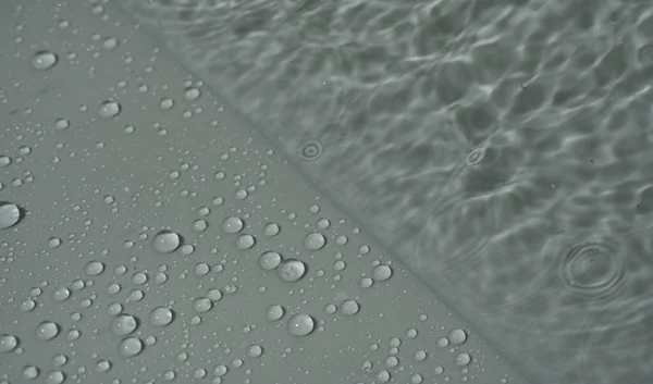 La textura de la gota de agua y el agua dividen el fondo gris en dos. Primer plano. —  Fotos de Stock
