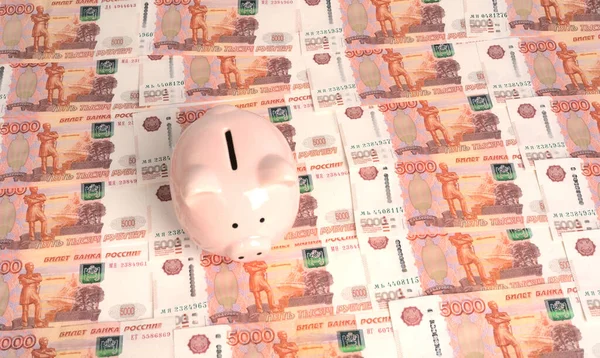 En spargris i form av en rosa gris står på konsistensen av femtusen rubel räkningar. — Stockfoto