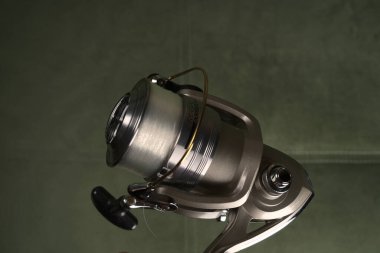 Moskova, Rusya - 8 Haziran 2021: Üzerinde şeffaf bir olta yarasıyla balıkçılık sporu için tasarlanmış metal bir makara. - Yakın çekim. Metin için boşluk