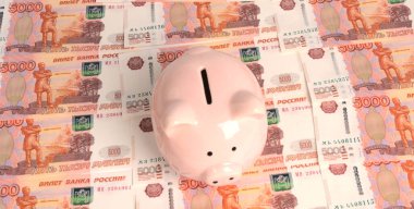 Pembe domuz şeklinde bir kumbara, beş bin rublelik banknotların dokusunda duruyor..