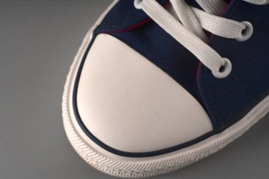 Gri arka planda beyaz ve mavi spor ayakkabılar..