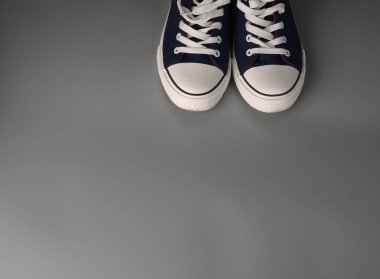 Gri arka planda beyaz ve mavi spor ayakkabılar.