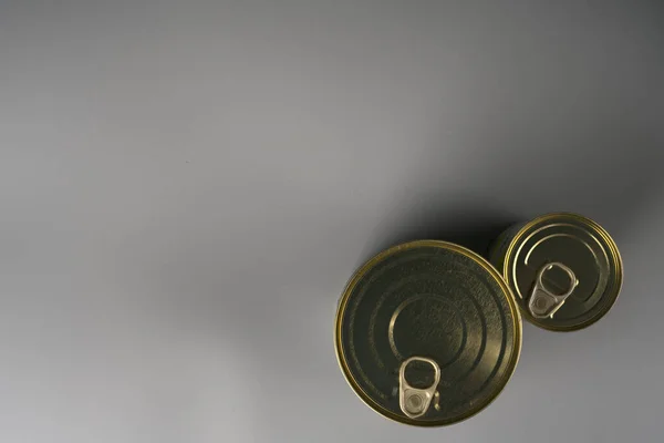 Twee aluminium blikjes van gouden kleur op een grijze achtergrond. — Stockfoto