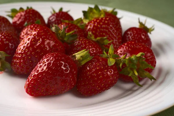 Jugosas fresas rojas yacen en un plato blanco Imagen de stock