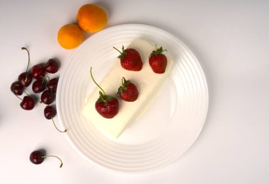 Beyaz dondurma sulu çilekli beyaz bir tabakta..