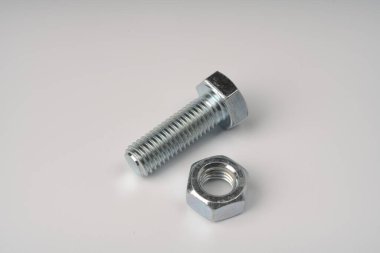 Büyük metal işlemeli bir cıvata ve beyaz arka planda yan yana duran bir fındık..