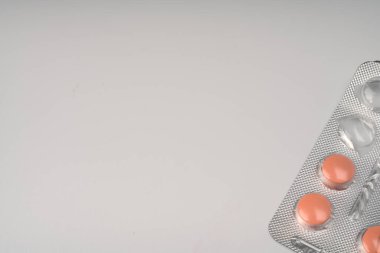 Beyaz arka planda gümüş su toplayan turuncu renkli tabletler..