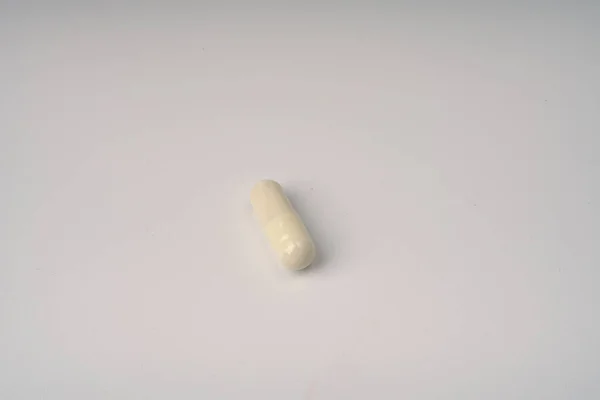 Um comprimido cápsula sobre um fundo branco close-up. — Fotografia de Stock