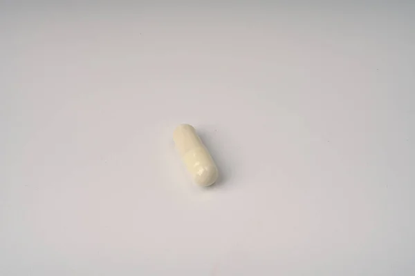 One tablet capsule on a white background closeup. Imágenes de stock libres de derechos