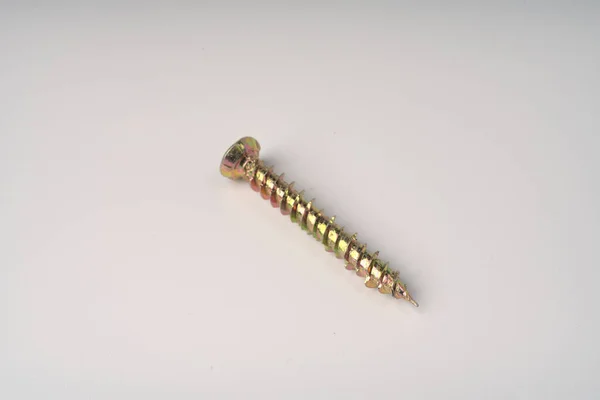 A long construction self-tapping screw of golden color on a white background. — Stock Photo, Image