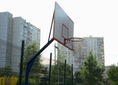 Sokakta bir basketbol potası çok parlak bir sabah güneşinin arka planında.