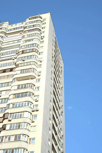 Een hoogbouw wordt overdag van onderaf gezien tegen de achtergrond van de blauwe lucht. Ruimte voor de tekst — Stockfoto