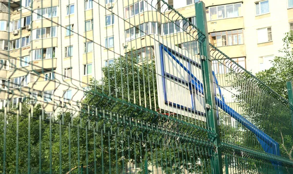 Ein Basketballschild auf einem Straßenplatz wird von hinten durch ein Netz betrachtet — Stockfoto