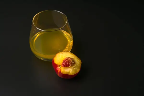 Κίτρινη σόδα σε διάφανο ποτήρι και κομμένο νεκταρίνι σε μαύρο φόντο. — Φωτογραφία Αρχείου