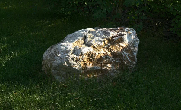 Duży kamień leży na zielonej trawie w parku miejskim. — Zdjęcie stockowe