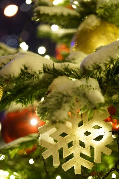 Speelgoed in de vorm van een sneeuwvlok weegt op de takken van een kerstboom. — Stockfoto