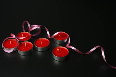 Altı tane küçük kırmızı mum var ve biri yanıyor. Pembe kurdele..