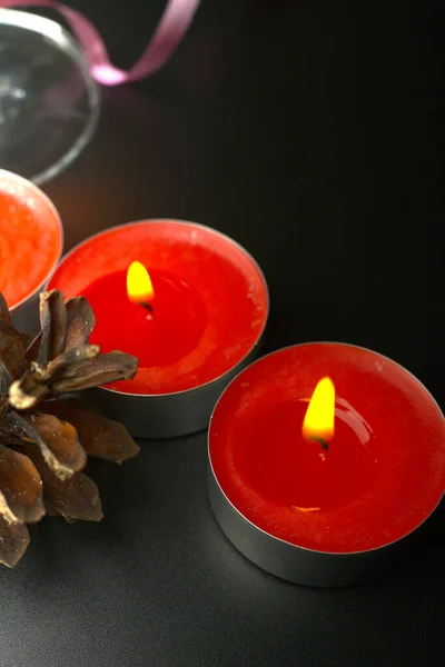 Cones de abeto com pequenas velas vermelhas e o caule de uma taça de champanhe closeup — Fotografia de Stock