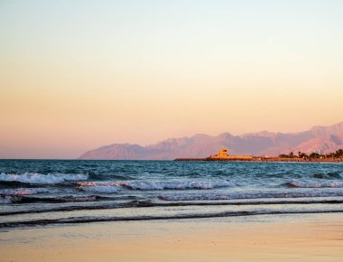Gün batımında sahildeki dalgaları ve kayalık sahili görmek. Ras Al Khaimah Emirlik 'te çekilmiş. BAE. Açık havada.