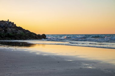 Gün batımında sahildeki dalgaları ve kayalık sahili görmek. Ras Al Khaimah Emirlik 'te çekilmiş. BAE. Açık havada.