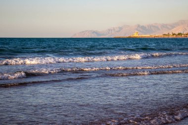 Sahilde, arkasında dağlar olan bir dalganın görüntüsü. Ras Al Khaimah Emirlik 'te çekilmiş. BAE. Açık havada.