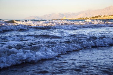 Sahilde, arkasında dağlar olan bir dalganın görüntüsü. Ras Al Khaimah Emirlik 'te çekilmiş. BAE. Açık havada.