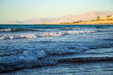 Sahilde, arkasında dağlar olan bir dalganın görüntüsü. Ras Al Khaimah Emirlik 'te çekilmiş. BAE. Açık havada.