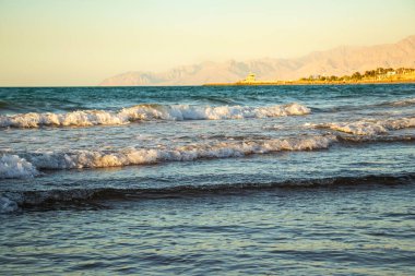 Sahilde, arkasında dağlar olan bir dalganın görüntüsü. Ras Al Khaimah Emirlik 'te çekilmiş. BAE. Açık havada.