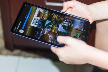 Dubai, BAE - 03.31.2021 Eller Samsung Galaksisi S6 hafif tabletini tutuyor, Instagram 'a göz atıyor