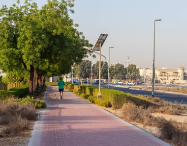 Dubai, BAE - 05.21.2021 Nad Al Hamar parkında orta yaşlı bir adam koşu parkında sabah erken saatlerde koşuyor. Resimde güneş panellerinden güç alan lamba direği görülebilir.
