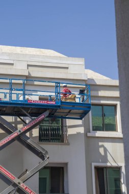 Dubai, BAE - Yükseklerde çalışan bir bakım işçisinin vurulması, Uluslararası şehir bölgesindeki binanın ön cephesinin onarılması.