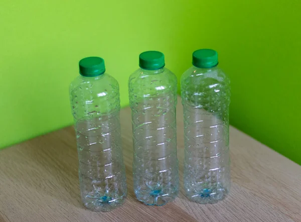 明るい緑の背景を持つ木製のテーブルの上にプラスチックボトルのショット — ストック写真