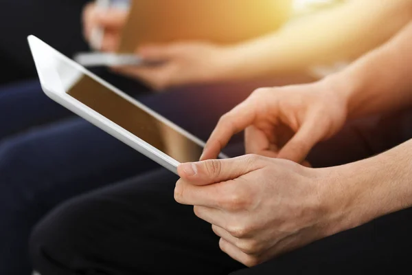 Group of casual dressed business people working at meeting or conference in sunny office, close-up of hands. Businessman using tablet computer — Stock Photo, Image