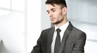 Modern ofiste bilgisayarla çalışan bir iş adamı. İş yerindeki bir erkek girişimcinin ya da müdürün vesikalığı. İş konsepti