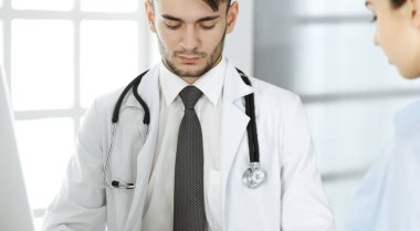 Doktor ve hasta. Tıp bürosunda ya da klinikte cam masada otururken ilaç kayıtlarını dolduran bir doktor. Tıp ve sağlık hizmetleri kavramı