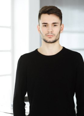 Modern ofiste sakallı adamın vesikalığı. İş adamı ya da öğrenci, dik durup gülümsüyor. Yaşam tarzı kavramı